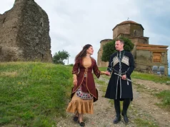 Gürcistan'da tarihi yapı önünde geleneksel kıyafetli Gürcü çift