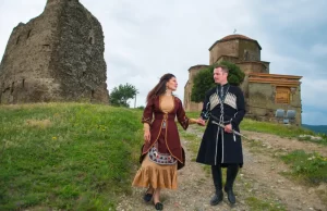Gürcistan'da tarihi yapı önünde geleneksel kıyafetli Gürcü çift