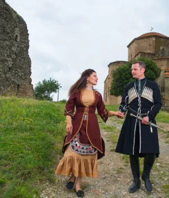 Gürcistan'da tarihi yapı önünde geleneksel kıyafetli Gürcü çift